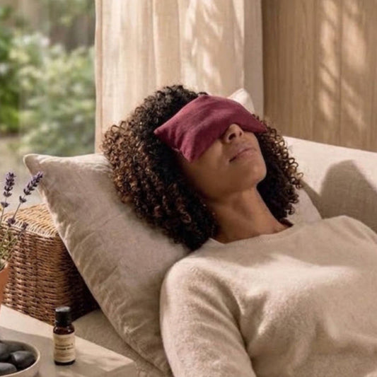 Woman lying on sofa with red eye pillow over her eyes